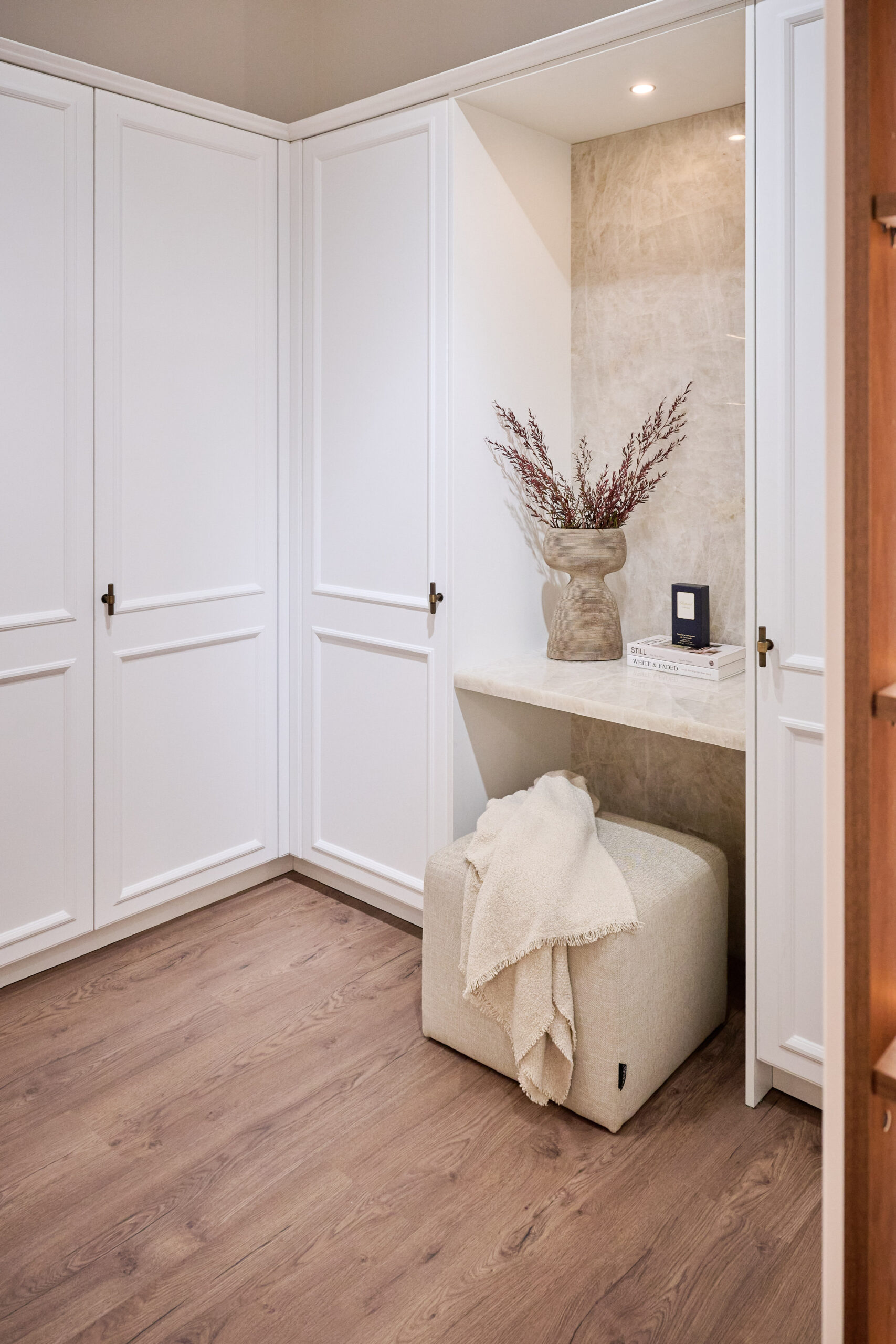 U-shaped wardrobe with white shaker cabinetry, timber-look interiors and downlights above a makeup desk